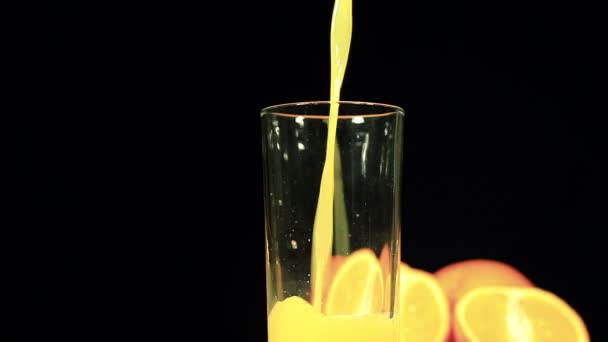 Sumo de laranja flui em vidro sobre fundo preto
 - Filmagem, Vídeo