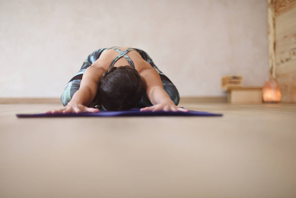 Mujer sobre esterilla con brazos y manos extendidas en yoga asana. Fondo de yoga - Foto, imagen