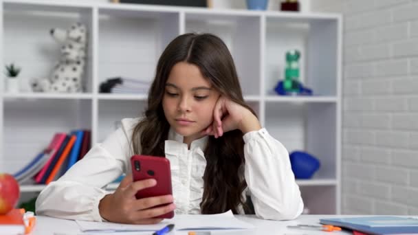 serious child chatting using smartphone in classroom, school. - Footage, Video