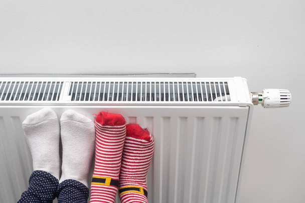 Οικογενειακή θέρμανση πόδια κοντά θερμάστρα στο σπίτι, closeup. - Φωτογραφία, εικόνα