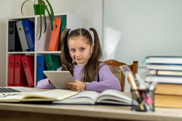本とコンピュータを備えた机の上の教室で美しい少女の肖像画。学習の概念です。学校だ。学校の時間 - 写真・画像
