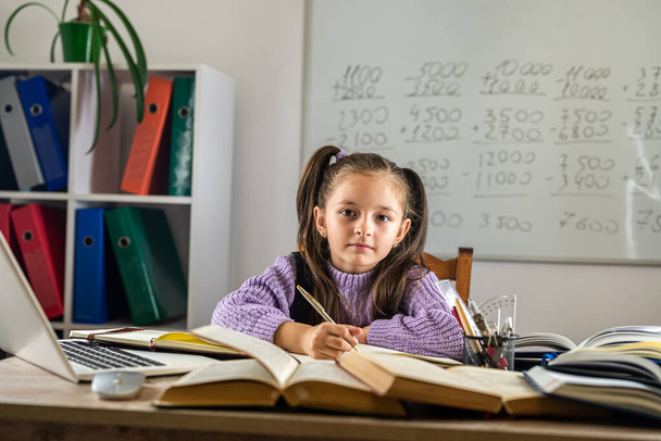 Lächelndes kleines kaukasisches Mädchen beim Videoanruf im fernen Klassenzimmer mit dem Laptop des Lehrers. fröhliches kleines Kind aufgeregten Gruß mit Tutor. Studien online am Computer. Heimschulkonzept - Foto, Bild