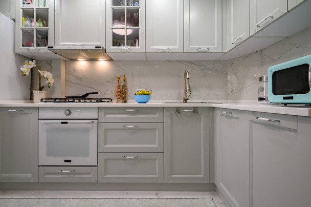 Nuovo grigio chiaro moderno ben progettato interno della cucina dopo la ristrutturazione, vista frontale e coner - Foto, immagini