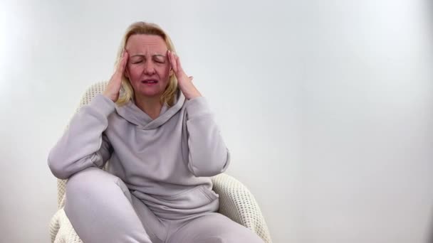 A woman holds head with his hands. Sensation of headache, migraine and dizziness. Headaches from stress or overwork. On examination by a doctor Close-up of woman who is worried about migraines - Footage, Video