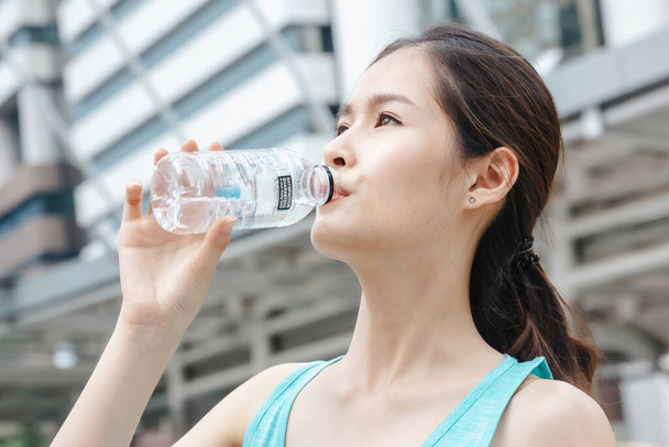 Asian lady drinking water sport healthy lifestyle outdoors in building city background - Photo, Image