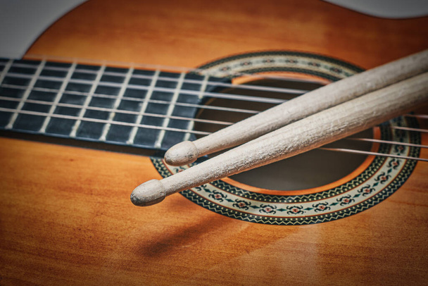 Detail of drumsticks affixed to an acoustic guitar - Photo, Image
