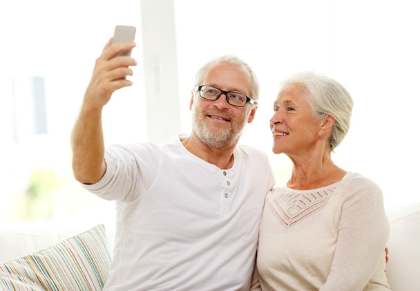 happy senior couple with smartphone at home - 写真・画像