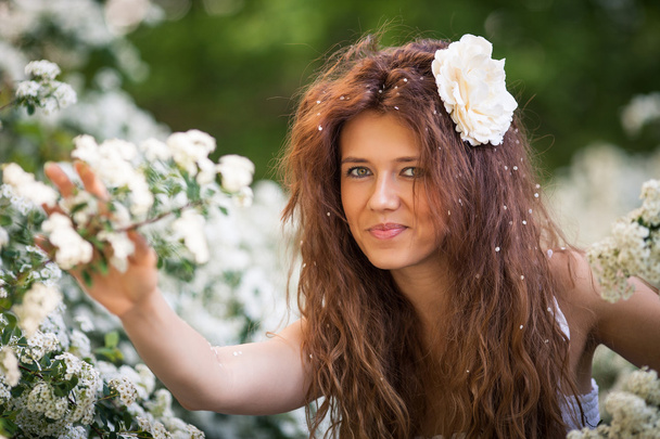 Πορτρέτο του γοητευτική νεαρή γυναίκα με όμορφο χαμόγελο άνοιξη κήπο γεμάτο άσπρα λουλούδια - Φωτογραφία, εικόνα