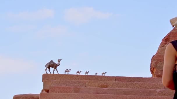 Petra, Jordanien - 7. Oktober 2022: Kamel-Metallfiguren in verschiedenen Größen stehen im Wohnwagen auf der Treppe vor einem Souvenirladen - Filmmaterial, Video