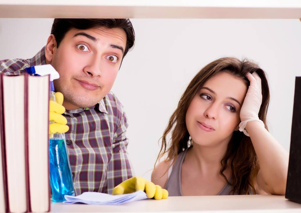 A esposa e o marido limpam o pó da estante - Foto, Imagem