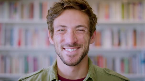 Face, bookshelf and man with smile, library and higher education with confidence, knowledge or academic. Male from the Netherlands, student or books for learning, studying or career success on campus. - Footage, Video