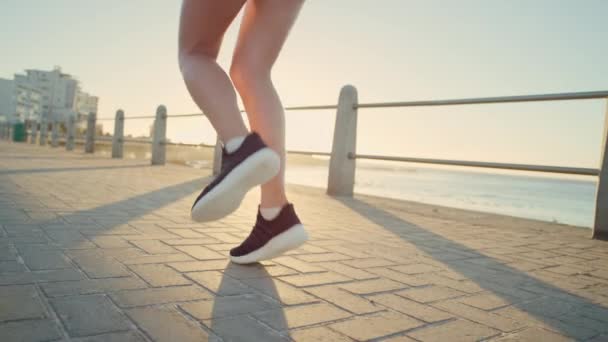 Lopende schoenen, benen en lichaam van de vrouw op de strandpromenade voor zonsondergang workout, warm up en cardiotraining tijdens het luisteren naar muziek. Runner op zee voor fitness in Miami voor gezondheid en welzijn. - Video