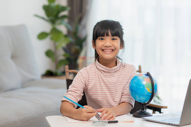 Azjatycka dziewczynka uczy się modelu globu, koncepcji ratowania świata i uczenia się poprzez zabawę dla edukacji dzieci w domu. - Zdjęcie, obraz
