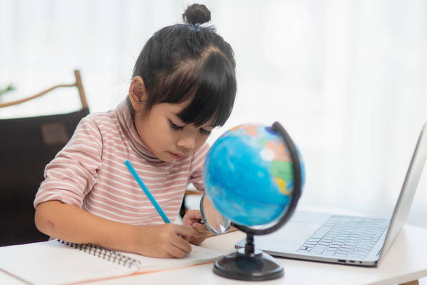 Ázsiai kislány tanul a földgömb modell, koncepció megmenteni a világot, és tanulni a játék tevékenység a gyerek oktatás otthon. - Fotó, kép