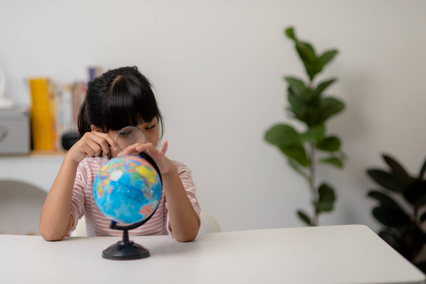 Ασιατικό κοριτσάκι μαθαίνει το μοντέλο κόσμο, έννοια της σώσει τον κόσμο και να μάθουν μέσα από το παιχνίδι δραστηριότητα για την εκπαίδευση των παιδιών στο σπίτι. - Φωτογραφία, εικόνα