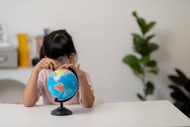 Asiatisches kleines Mädchen lernt das Globus-Modell, das Konzept, die Welt zu retten und durch Spielaktivitäten für die Kindererziehung zu Hause zu lernen. - Foto, Bild