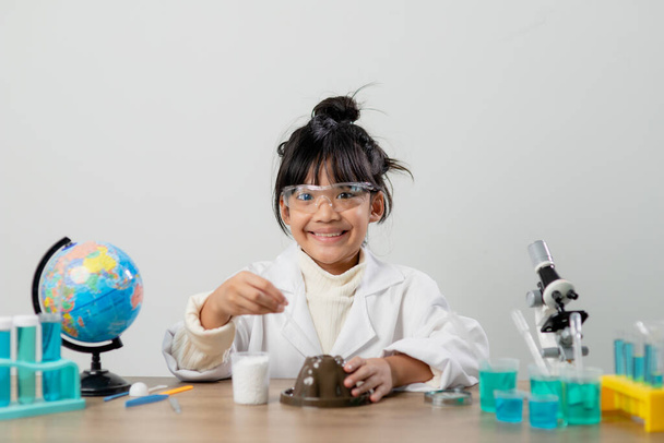 εκπαίδευση, επιστήμη, χημεία και παιδιά έννοια - τα παιδιά ή τους μαθητές με δοκιμαστικό σωλήνα καθιστώντας πείραμα στο σχολικό εργαστήριο - Φωτογραφία, εικόνα