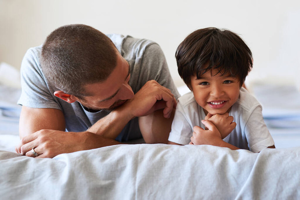 Un retard de croissance comme mon père. Portrait d'un adorable petit garçon couché sur le lit avec son père à la maison - Photo, image