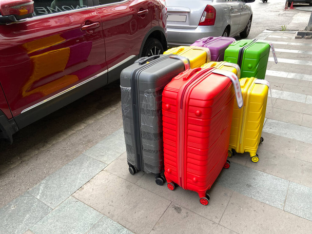 muchas maletas modernas coloridas diferentes que permanecen cerca del coche, conjunto de maletas, pila de maletas de viaje nuevas maletas apiladas, al aire libre - Foto, Imagen