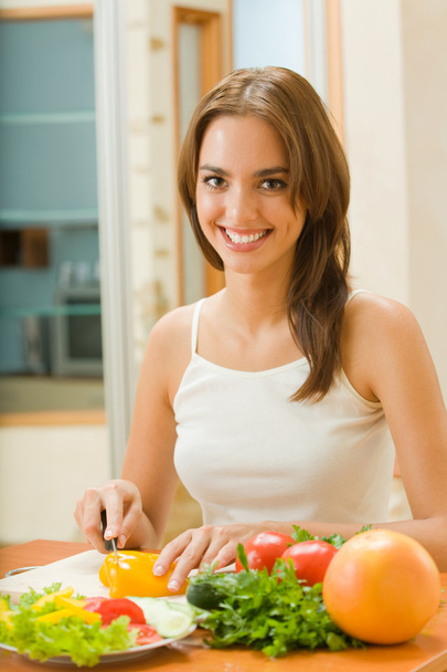 Young happy woman making salad at domestic kitchen - Fotoğraf, Görsel