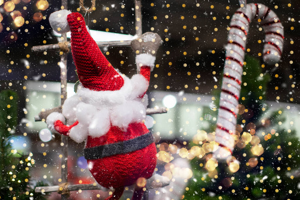 On a Christmas background, a toy santa claus climbs a rope ladder against a background of golden bokeh. - Photo, Image