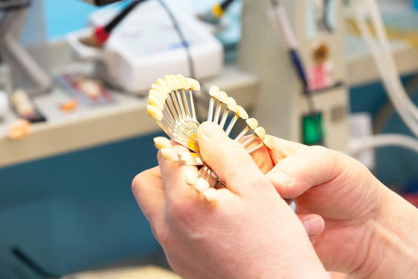 Une palette pour déterminer la couleur des dents dans les mains d'un orthopédiste dentaire. - Photo, image