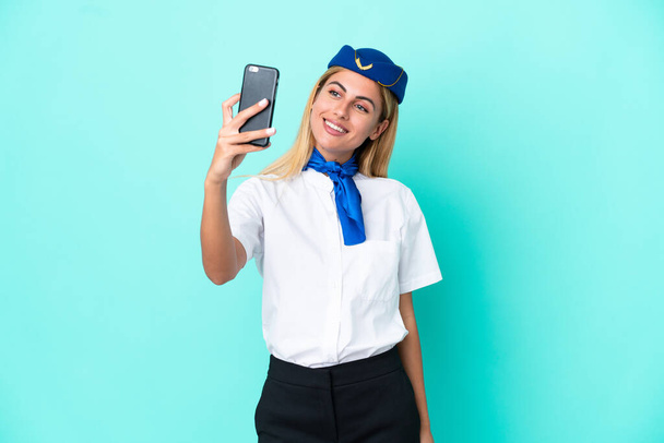 stewardessa samolotu urugwajska kobieta odizolowana na niebieskim tle robi selfie - Zdjęcie, obraz
