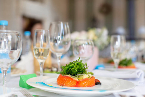Detailní záběr na kus červené ryby zdobený rukolou na talíři v restauraci. - Fotografie, Obrázek