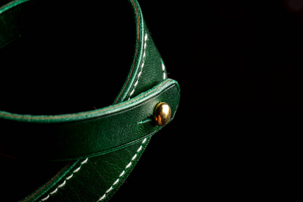 Part of a leather product or belt in green on a black background. - Photo, Image
