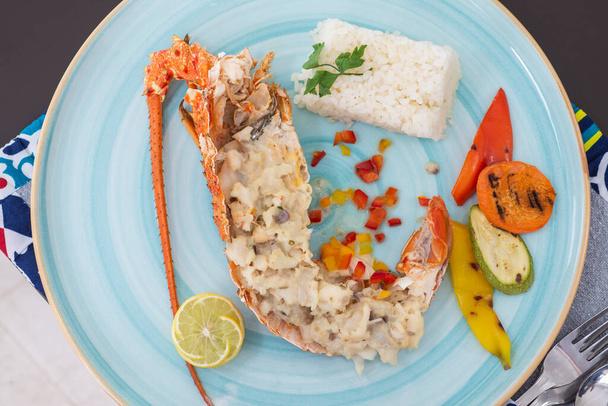 Фаршированное блюдо из омаров а ля карт с белым рисом и овощами за столом ресторана - Фото, изображение