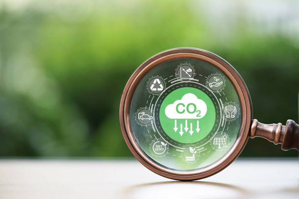 CO2 redukční ikona uvnitř lupy na zeleném pozadí pro snížení CO2, uhlíkové stopy a uhlíkového kreditu pro omezení globálního oteplování v důsledku změny klimatu, Bio Circular Green Economy koncept. - Fotografie, Obrázek
