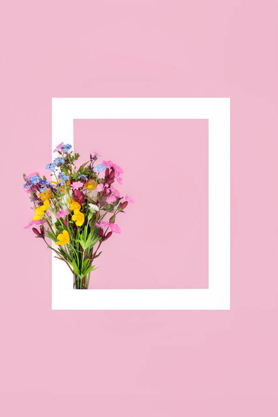 Lente wilde bloem posy, wit frame op roze achtergrond. Minimale abstracte grens natuur compositie voor Valentijnsdag, Moederdag, Pasen, verjaardag. Britse flora. Vlakke plaat. - Foto, afbeelding