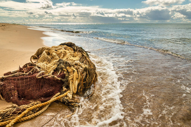Una red de pesca de pico arrastrada a la orilla del mar. Una red enredada yace en una playa de arena. Mar Báltico, Península de Hel, Pomerania, Hel, Polonia - Foto, imagen