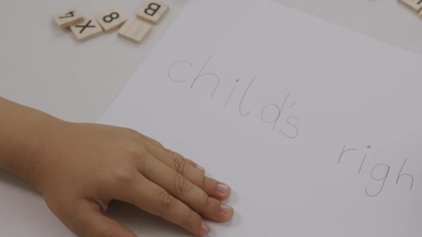 Slovo DĚTÍ PRÁVA napsaná dítětem na papír. Vysoce kvalitní 4K záběry - Záběry, video
