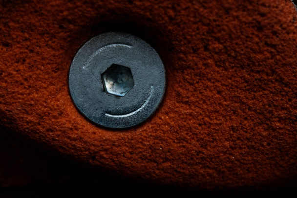 Großaufnahme von künstlichem roten Klettergerüst an einer Ziegelwand. Sehr raue Textur. Tapete und Mikro-Ansicht der Schraube. - Foto, Bild