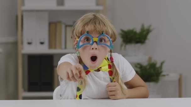 Ragazza divertente di 7 anni vestita con occhiali da clown, farfalla e bretelle. Filmati 4k di alta qualità - Filmati, video