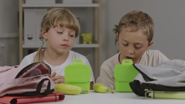 Menino e menina estão comendo seus lanches na mesa. Imagens 4k de alta qualidade - Filmagem, Vídeo