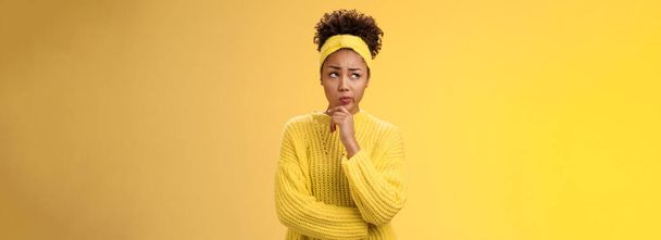 Вы не уверены, обеспокоенный милый африканско-американская девушка сталкивается жесткое решение посмотреть вдумчивый план, думая, как действовать право касания подбородок, сделать предположение стоя обеспокоенный желтый фон. - Фото, изображение