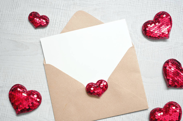 Blank white greeting card with brown envelop and hearts on marble table. Mockup valentines day concept - Photo, Image