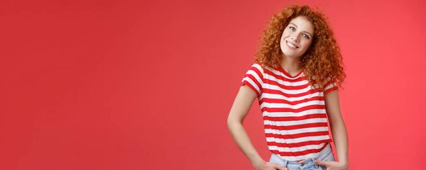 Lifestyle. Cheerful european redhead fashionable happy redhead curly-haired girl tilt head excited hold hands jeans pockets smiling broadly toothy glad grin enjoy summer vibes romantic girlfriend date - Photo, Image
