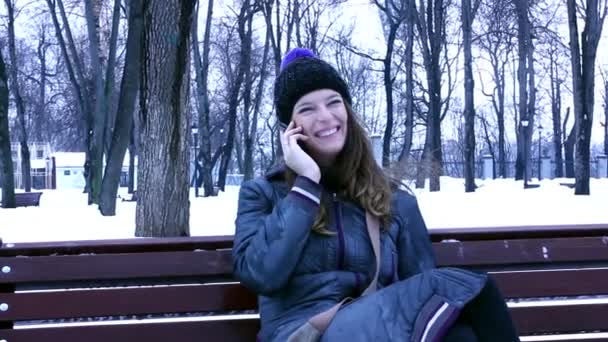 Jovem menina agradável fala por telefone celular no parque de inverno
 - Filmagem, Vídeo