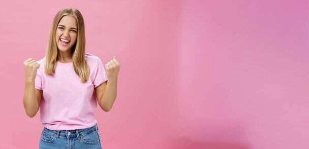 Так, я це зробив. Портрет щасливої в захваті успішної молодої студентки, яка отримує нагороду тріумфуючи, збуджуючись і радісно піднімаючи кулаки в підбадьорюванні, дивлячись впевнено на камеру над рожевою стіною
 - Фото, зображення