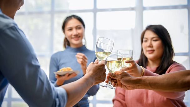 Grupa azjatyckich przyjaciół ma imprezę w domu, świętowanie, przyjęcie urodzinowe, picie i brzęczenie kieliszki z winem razem. - Zdjęcie, obraz