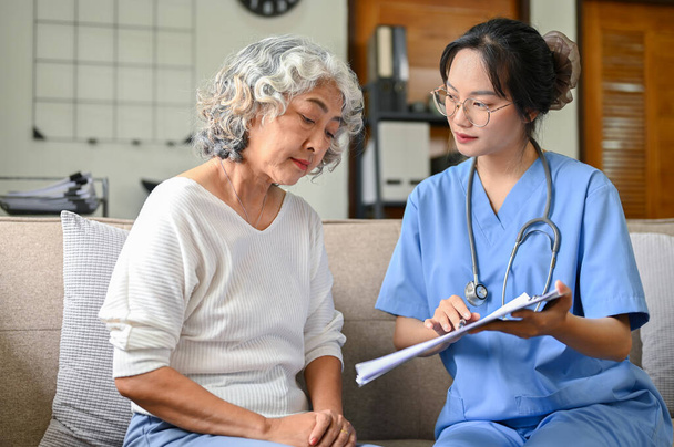 A 60-year-old elderly retire woman and her doctor having a serious talk, consulting about her surgery and treatment plan in the hospital office. - Photo, Image