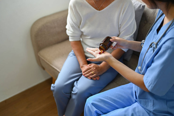 Cuidados e tipo cuidador feminino ou enfermeiro dando um medicamento para seu paciente idoso. imagem recortada - Foto, Imagem