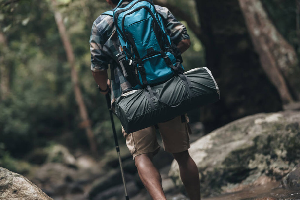Hikers use trekking pole with backpacks walking through the rock and water on stream in the forest. hiking and adventure concept. - Foto, imagen