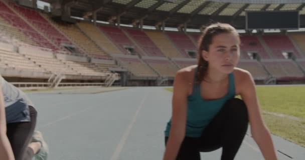 Three young people preparing to race each other at the race track on a stadium - Footage, Video
