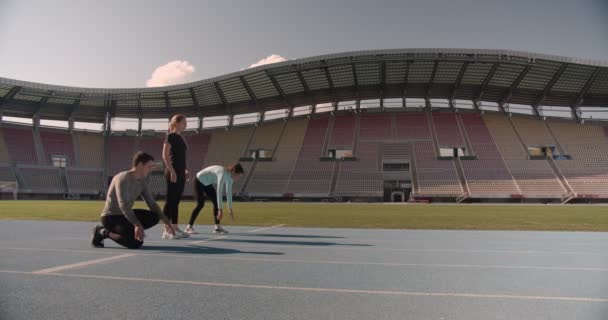 Three young people compete on the running track at a stadium - Footage, Video