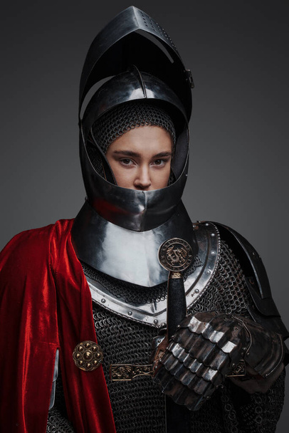 Портрет лицарки з мечем і червоним плащем ізольовані на сірому фоні
. - Фото, зображення