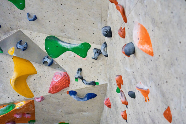 Wand zum Bouldern in der Sporthalle mit Griffen zum Klettern. Aktives Extremsportkonzept - Foto, Bild